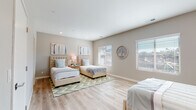 Located at 1470 S Santa Fe Ave in Vista, CA, this single-floor space centers around a generously sized bedroom designed to accommodate multiple occupants comfortably. The room is finished with light-toned luxury vinyl plank flooring that runs throughout, contributing to a clean, cohesive aesthetic. Neutral warm-gray walls provide a calming backdrop, complemented by recessed lighting that ensures consistent illumination across the space.

Multiple windows fitted with white horizontal blinds line the walls, inviting abundant natural light and offering views of the surrounding outdoor environment. The room provides ample floor space to house several beds without feeling crowded, making it well-suited for shared living arrangements. Decorative wall art in soft coastal tones adds a welcoming, curated touch to the interior.

Storage is addressed through a dedicated walk-in closet, accessible directly from the bedroom, featuring built-in shelving and hanging rods. A second door leads to an additional room or hallway, further enhancing the functional layout. The overall ambiance of the space is bright, airy, and thoughtfully appointed, reflecting a modern design sensibility suited to comfortable, practical living.