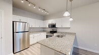 Located at 204 Lightbourne in Spartanburg, SC, this single-story, one-bedroom, one-bathroom residence offers a well-designed layout with modern finishes throughout. Light wood-style flooring flows seamlessly across every room, creating a cohesive and clean aesthetic.

The open-concept kitchen and living area serves as the heart of the home. The kitchen is outfitted with crisp white shaker cabinetry, granite countertops, stainless steel appliances including a refrigerator, range, and microwave, and a peninsula with an undermount sink. Pendant lighting and a track light fixture illuminate the space stylishly. The adjacent living area benefits from natural light and offers a comfortable, open feel with a ceiling fan overhead.

The bedroom is generously sized, featuring a window with exterior views, neutral walls, and continued wood-style flooring. A dedicated walk-in closet provides ample storage with wire shelving systems installed throughout. The full bathroom features a granite-topped vanity with an undermount sink and a full tub/shower combination, all finished in a clean, neutral palette.

Additional spaces include a hallway, a utility room, and convenient entry area. The overall ambiance is bright, modern, and move-in ready.