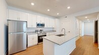 Located at 5151 Ebright Rd in Canal Winchester, Ohio, this single-floor, three-bedroom, two-bathroom home offers a well-designed layout that maximizes its comfortable footprint. The open-concept kitchen and living area serves as the heart of the home, showcasing crisp white shaker cabinetry, granite countertops, and a central island with a built-in sink — ideal for both meal prep and casual dining. Stainless steel appliances, including a refrigerator, range, and over-the-range microwave, complete the kitchen. Warm hardwood-style flooring flows throughout the main living areas, adding continuity and a welcoming feel. Natural light filters into the living room through a front-facing door and window combination, brightening the space. The bedrooms are finished with plush carpet and neutral tones, providing a calm retreat. The primary bedroom offers a notably generous footprint with a dedicated walk-in closet featuring wire shelving. A second closet is found in another bedroom, providing ample storage throughout. The two bathrooms are clean and modern, with one featuring a walk-in glass-door shower, wood-look flooring, granite vanity, and white tile surround. A connecting hallway ties the layout together efficiently, making this a functional and move-in-ready home.