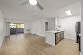 This well-appointed 2-bedroom, 1-bathroom unit is laid out on a single floor, offering a clean and modern aesthetic throughout. Light hardwood-style flooring runs continuously across all rooms, creating a cohesive and airy feel.

The open-concept kitchen and living area forms the heart of the unit. The kitchen is outfitted with stainless steel appliances — including a refrigerator, range, microwave, and dishwasher — paired with white shaker cabinetry, sleek light countertops, and a deep stainless steel sink. A ceiling fan serves the adjacent living area, which is generously sized and receives abundant natural light through large sliding glass doors that open onto a private outdoor patio with greenery views.

The primary bedroom is notably spacious, featuring a window with vertical blinds, a baseboard heater, and floor-to-ceiling mirrored sliding closet doors. The second bedroom is similarly bright, also with a window and light flooring. A dedicated closet with built-in shelving provides additional storage along the hallway.

The bathroom maintains the home's clean, white palette with a white vanity, light flooring, and chrome fixtures. Throughout, the textured white ceilings and crisp white walls give the entire unit a fresh, move-in-ready appearance.