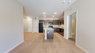 This well-appointed single-story home offers 3 bedrooms and 2 bathrooms across a thoughtfully designed floor plan. The open-concept kitchen and living area serves as the heart of the home, where rich dark-stained cabinetry contrasts beautifully with light granite countertops and a central island that provides additional prep space and seating. Black appliances, including a refrigerator, range, microwave, and dishwasher, complete the kitchen. Light wood-style flooring flows seamlessly throughout the main living areas and bedrooms, creating a cohesive and modern aesthetic. The living room is bright and airy, featuring a ceiling fan and French doors that invite natural light and outdoor access. The generously sized primary bedroom includes its own ceiling fan, a closet, and connects to a well-designed en-suite bathroom boasting a dual-sink granite vanity with dark wood cabinetry, large-format tile flooring, and open built-in shelving for additional storage. The additional bedrooms are comfortably sized with light-filled windows and closet access. The secondary bathroom mirrors the same quality finishes found throughout. Neutral tones, recessed lighting, and clean architectural lines give this home a fresh, move-in-ready appeal.