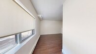 Located at 4141 Bathurst Street in Toronto, this one-bedroom, one-bathroom unit offers a well-organized single-floor layout designed for comfortable everyday living. The open-concept kitchen and living area form the heart of the space, where crisp white shaker-style cabinetry, stainless steel appliances — including a full-size refrigerator and stove — and light tile flooring create a clean, functional cooking environment. The kitchen flows naturally into the living area, which transitions to rich, dark hardwood-style flooring that extends throughout the remainder of the unit. The bedroom is a quiet retreat, featuring the same warm hardwood-style floors, white walls, baseboard heating, and a ground-level window that frames a pleasant view of surrounding greenery, bringing a touch of nature into the room. An additional windowed room provides flexible living or lounge space, also finished with hardwood-style floors and a bright, neutral palette. The bathroom is finished with large-format neutral tile surrounding a full soaker tub and shower combo with chrome fixtures, lending a polished and contemporary feel. Throughout the unit, clean white walls, consistent flooring, and an efficient layout come together to create a cohesive and practical living environment.