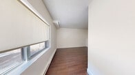 Located at 4141 Bathurst Street in Toronto, this one-bedroom, one-bathroom unit offers a well-organized single-floor layout designed for comfortable everyday living. The open-concept kitchen and living area form the heart of the space, where crisp white shaker-style cabinetry, stainless steel appliances — including a full-size refrigerator and stove — and light tile flooring create a clean, functional cooking environment. The kitchen flows naturally into the living area, which transitions to rich, dark hardwood-style flooring that extends throughout the remainder of the unit. The bedroom is a quiet retreat, featuring the same warm hardwood-style floors, white walls, baseboard heating, and a ground-level window that frames a pleasant view of surrounding greenery, bringing a touch of nature into the room. An additional windowed room provides flexible living or lounge space, also finished with hardwood-style floors and a bright, neutral palette. The bathroom is finished with large-format neutral tile surrounding a full soaker tub and shower combo with chrome fixtures, lending a polished and contemporary feel. Throughout the unit, clean white walls, consistent flooring, and an efficient layout come together to create a cohesive and practical living environment.