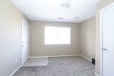 This single-floor residential unit offers a practical and well-organized layout designed for comfortable everyday living. The interior is finished with warm neutral tones — predominantly beige and tan — across the walls, complemented by soft wall-to-wall carpeting in the living and bedroom areas, and hard flooring in the kitchen and bathrooms.

The living area is generously proportioned, featuring a window that allows natural light to fill the space. A refrigerator is conveniently positioned at the transition point between the living area and kitchen, indicating an open and accessible flow between the two zones. The kitchen is equipped with light wood cabinetry providing ample storage, a double sink, an electric range with overhead ventilation, and a dishwasher, all set against light countertops and durable tile flooring.

The unit includes two bedrooms, each carpeted and finished with the same neutral palette. One bedroom features a sliding-door closet with a built-in rod for hanging storage, and a window fitted with horizontal blinds. Both rooms offer a calm and functional environment.

Two full bathrooms serve the unit, each identically appointed with a combination tub and shower, a light wood vanity with a countertop, tile flooring, and chrome fixtures. The layout ensures convenient access from the main living areas. Overall, this unit delivers a clean, functional, and move-in-ready space.