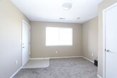 This single-floor residential unit offers a practical and well-organized layout designed for comfortable everyday living. The interior is finished with warm neutral tones — predominantly beige and tan — across the walls, complemented by soft wall-to-wall carpeting in the living and bedroom areas, and hard flooring in the kitchen and bathrooms.

The living area is generously proportioned, featuring a window that allows natural light to fill the space. A refrigerator is conveniently positioned at the transition point between the living area and kitchen, indicating an open and accessible flow between the two zones. The kitchen is equipped with light wood cabinetry providing ample storage, a double sink, an electric range with overhead ventilation, and a dishwasher, all set against light countertops and durable tile flooring.

The unit includes two bedrooms, each carpeted and finished with the same neutral palette. One bedroom features a sliding-door closet with a built-in rod for hanging storage, and a window fitted with horizontal blinds. Both rooms offer a calm and functional environment.

Two full bathrooms serve the unit, each identically appointed with a combination tub and shower, a light wood vanity with a countertop, tile flooring, and chrome fixtures. The layout ensures convenient access from the main living areas. Overall, this unit delivers a clean, functional, and move-in-ready space.