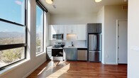 Located at 603 S Cascade Ave in Colorado Springs, Colorado, this single-floor unit offers a thoughtfully designed layout with modern finishes and an open, airy atmosphere. Large floor-to-ceiling windows flood the living and kitchen areas with abundant natural light while framing scenic outdoor views of the surrounding Colorado landscape, including glimpses of the mountains.

The kitchen is a standout feature, showcasing a two-tone cabinet design with white upper cabinets and gray lower cabinets, complemented by gold hardware accents. A decorative tile backsplash adds texture, while a full suite of stainless steel appliances—including a refrigerator, range, microwave, and dishwasher—provides functional, contemporary appeal. Warm hardwood-style flooring runs consistently throughout the unit, enhancing cohesion across each space.

The additional rooms offer clean, neutral walls and generous proportions, providing versatile living areas bathed in natural light. An electrical panel is conveniently integrated into one of the rooms.

The bathroom is finished with refined details, including large-format marble-style wall tiles surrounding a soaking tub and shower combination, natural stone-look floor tiles, a white vanity with gold hardware, and matte black fixtures, creating an elegant yet understated aesthetic throughout.