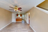 Located at 208 Southwind Dr in Athens, Alabama, this two-story home offers a practical and comfortable layout spread evenly across two floors. The main level opens into a spacious living area with light-toned hardwood-style flooring, warm beige walls, a textured ceiling, and a ceiling fan with light fixture — creating a bright, welcoming atmosphere. The kitchen flows directly from the living space and is well-appointed with warm oak cabinetry, white countertops, a stainless steel range, dishwasher, refrigerator, and a skylight-style overhead light panel that keeps the space bright. A peninsula counter adds functional separation between the kitchen and living areas. The home includes two full bathrooms, each featuring a single-sink vanity with wood cabinetry and a tub-shower combination. Four closets throughout the home provide ample storage. The bedrooms are generously sized, with hardwood-style flooring, ceiling fans, and windows that let in natural light with views of surrounding greenery. A dedicated laundry area and staircase connecting both floors round out the home's practical layout. Clean finishes, neutral tones, and consistent flooring throughout contribute to a cohesive, move-in-ready feel.