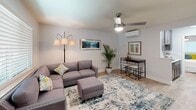 Located at 3531 Plantation Way in Naples, FL, this one-bedroom, one-bathroom unit offers a thoughtfully organized layout across a single floor. Light wood-style flooring runs throughout, creating a cohesive and clean aesthetic in every room.

The living room serves as the central gathering space, featuring a ceiling fan, a natural light-admitting window with blinds, and a wall-mounted mini-split HVAC unit. The open layout comfortably accommodates a sectional sofa and a small dining area, making efficient use of the available space.

The galley-style kitchen is well-equipped with dark espresso cabinetry, quartz-style countertops, a double stainless steel sink, and a full suite of stainless steel appliances including a refrigerator, electric range, and built-in microwave. The kitchen opens directly toward the bedroom, promoting easy flow through the unit.

The bedroom features a ceiling fan, a window with blinds for natural light, a wall-mounted mini-split unit, and a sliding-door closet. A partial view into the bathroom is accessible directly from the bedroom, adding convenience.

The bathroom includes a tub-shower combination with built-in shelving and chrome fixtures, paired with dark cabinetry and a vanity mirror. The overall ambiance of the unit is bright, clean, and functional.