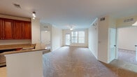 Located at 9734 Tapestry Park Cir in Jacksonville, Florida, this single-floor residence offers a thoughtfully designed layout with a warm, neutral color palette throughout. The expansive main living area is finished with plush carpeting, crown molding, and a ceiling fan, creating a comfortable and airy atmosphere. Natural light flows in through large windows with blinds that overlook the exterior, while a set of glass doors provides direct outdoor access. The kitchen is a standout feature, showcasing rich cherry wood cabinetry, granite countertops, a peninsula breakfast bar, and stainless steel appliances including an electric range and built-in microwave, all set atop classic tile flooring. The bedrooms are generously sized with soft carpeting and ample ventilation. The primary bathroom is well-appointed with a double-sink vanity set in matching cherry wood cabinetry with granite tops, a soaking tub, and a separate glass-enclosed shower. A secondary bathroom provides a tub-shower combination with tile surround. A dedicated utility room houses a stacked front-loading washer and dryer alongside wire shelving for additional storage. The overall ambiance is clean, functional, and move-in ready.