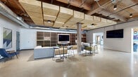 Located at 470 Market Ave SW in Grand Rapids, Michigan, this thoughtfully renovated single-floor space blends industrial heritage with modern design across a generously sized footprint. Exposed heavy timber beams, wood plank ceilings, and visible ductwork pay homage to the building's industrial roots, while polished concrete floors and crisp white walls create a clean, contemporary atmosphere throughout.

The main living and lounge area is an open, airy expanse anchored by a striking honeycomb-patterned wood feature wall with an integrated display screen. Large grid-pane windows flood the space with natural light, and a mix of seating arrangements—including plush yellow sofas, round tables with amber chairs, and bar-height seating—offer flexible social and work configurations. A black metal planter with live greenery adds a natural focal point to the open floor plan.

A dedicated collaborative zone features carpet-tiled flooring, bold geometric wallcovering, pendant lighting, and a glass-enclosed phone booth for private calls. A beverage nook with tile backsplash and cabinetry provides a convenient refreshment station nearby.

The well-appointed exercise room is a standout amenity, offering rubber flooring, full-wall mirrors, a comprehensive selection of cardio machines and strength equipment, and abundant natural light from oversized industrial windows. The hallway and supporting rooms connect the areas seamlessly, completing this versatile and dynamic space.
