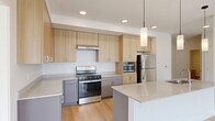 This well-designed 2-bedroom, 2-bathroom residence offers a clean, contemporary aesthetic throughout its single-level floor plan. Light hardwood flooring flows seamlessly across the main living areas, complementing the bright, white walls and recessed lighting that give the space an open, airy feel.

The kitchen is a standout feature, equipped with stainless steel appliances including a gas range, built-in microwave, and refrigerator. Light wood cabinetry extends to the ceiling for ample storage, while gray lower cabinets and granite-style countertops add a modern contrast. A peninsula with pendant lighting and an integrated sink serves as both a functional workspace and a casual gathering point, opening directly into the living area.

The primary bedroom is generously sized, featuring large windows that fill the room with natural light and views of the surrounding urban streetscape. A ceiling fan adds comfort and practicality. The second bedroom mirrors this bright, clean design with dual tall windows and hardwood floors.

Both bathrooms are finished with tile flooring and light wood vanities topped with granite countertops. The primary bath includes a full soaking tub and shower combination, while the second bath offers a walk-in shower configuration. A dedicated closet provides additional storage. Throughout the residence, the design prioritizes clean lines, natural light, and a cohesive, modern palette.