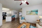 Located in Palm Bay, Florida, this single-floor, 2-bedroom, 2-bathroom residence offers a well-designed layout with a comfortable, coastal-inspired aesthetic. The open-concept living, dining, and kitchen area serves as the heart of the home, featuring wood-style hard flooring, textured ceilings, and ceiling fans throughout. The living room receives natural light through a large window dressed with sheer curtains, creating a bright and airy atmosphere.

The kitchen is equipped with white shaker-style cabinetry, granite countertops, black appliances including a refrigerator, range, and microwave, and a peninsula with bar seating that connects seamlessly to the dining area. A pantry and in-unit laundry add practical convenience.

Both bedrooms are carpeted and fitted with ceiling fans. The primary bedroom includes a closet and direct access to an en-suite bathroom. The second bedroom features a generously sized window with garden views. Each bathroom offers a tub/shower combination, white vanity cabinetry, granite countertops, and wood-style flooring, with one bathroom also featuring a well-lit vanity mirror. Two closets provide ample storage throughout the residence.