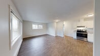 Located in Federal Way, WA, this 2-bedroom, 1-bathroom single-floor unit offers a clean, modern aesthetic throughout. The open-concept living and kitchen area is anchored by durable wood-style plank flooring and bright white walls, creating a light and airy atmosphere. Large windows allow natural light to fill the living space, which flows seamlessly toward the kitchen. The kitchen is well-appointed with crisp white shaker cabinetry, light stone-finish countertops, a stainless steel refrigerator, dishwasher, and range, providing both style and function. Both bedrooms feature soft wall-to-wall carpeting and sliding windows that offer views of the surrounding neighborhood. The primary bedroom includes a dedicated closet, while the unit benefits from a total of three closets for ample storage throughout. Baseboard heating is present in the bedrooms, ensuring comfort year-round. The bathroom includes a full soaking tub and shower combination with clean, neutral finishes. A hallway connects the living areas to the bedrooms and bathroom, contributing to an efficient and practical layout. The overall design is refreshed and move-in ready, with a neutral color palette that suits a wide range of furnishing styles.
