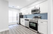 Located in Old Bridge, NJ, this thoughtfully updated two-floor home showcases a clean, modern aesthetic with consistent finishes throughout. The main level features an open-concept layout with light gray walls, recessed lighting, and durable light-toned luxury vinyl plank flooring that flows seamlessly from room to room. The kitchen is a standout, equipped with crisp white shaker cabinets, a light blue subway tile backsplash, white quartz countertops, matte black hardware, and a full suite of stainless steel appliances including a refrigerator, electric range, over-the-range microwave, and dishwasher. A staircase with dark wood railings connects the two levels. The upper floor offers well-proportioned rooms bathed in natural light from large windows fitted with blinds. Bedrooms include closet space, and the layout provides a practical flow between living areas. The bathroom features dark slate-style floor tiles, white walls, a white vanity with a quartz top, and an elegantly tiled herringbone wall accent in the shower area with matte black fixtures. A sliding door on the main level provides access to outdoor space. Throughout the home, white trim, six-panel doors with matte black hardware, and neutral tones create a cohesive, move-in ready environment.