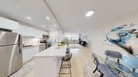 This well-designed 2-bedroom, 1-bathroom unit is laid out on a single floor, offering a cohesive and efficient use of space. The open-concept living and dining area forms the heart of the unit, characterized by light hardwood flooring, recessed lighting, and large windows fitted with roller shades that diffuse natural light throughout. The living room provides generous space for seating and entertaining, with a relaxed, airy ambiance.

The kitchen is modern and functional, featuring sleek white cabinetry, stainless steel appliances including a refrigerator, electric range, microwave, and dishwasher, along with a white countertop peninsula with bar seating — seamlessly connecting the kitchen to the main living area.

The primary bedroom is a comfortable, well-proportioned room with wide windows, a sliding-door closet, and the same light hardwood flooring found throughout the unit. The second bedroom offers a quieter retreat with neutral tones and a built-in closet. The bathroom is clean and bright, finished in white with a full tub-shower combination. A hallway connects all rooms, contributing to a practical and organized flow throughout the unit.