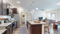 Located on Shannon Circle in Winter Haven, Florida, this single-story home offers a well-designed layout across three bedrooms, two bathrooms, a dedicated office, and an open-concept living, dining, and kitchen area. Light-toned luxury vinyl plank flooring flows throughout, tying each space together cohesively.

The kitchen is a standout feature, showcasing rich dark-espresso cabinetry, granite-look countertops, stainless steel appliances, and a large center island with pendant lighting overhead. It opens seamlessly into the dining area and living room, where a ceiling fan, natural light from large windows, and a glass door create a bright, welcoming atmosphere.

The living and dining areas offer generous room for entertaining, with the dining space accommodating a full-sized table and the living room providing comfortable gathering space. The office is bathed in natural light from multiple windows, making it ideal for focused work.

The primary bedroom features a ceiling fan, hardwood-style flooring, and natural light. Bathrooms mirror the kitchen's design language with dark cabinetry and granite countertops. A dedicated laundry room houses a full-sized washer and dryer. Two closets and additional storage round out this practical and stylish home.