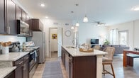 Located on Shannon Circle in Winter Haven, Florida, this single-story home offers a well-designed layout across three bedrooms, two bathrooms, a dedicated office, and an open-concept living, dining, and kitchen area. Light-toned luxury vinyl plank flooring flows throughout, tying each space together cohesively.

The kitchen is a standout feature, showcasing rich dark-espresso cabinetry, granite-look countertops, stainless steel appliances, and a large center island with pendant lighting overhead. It opens seamlessly into the dining area and living room, where a ceiling fan, natural light from large windows, and a glass door create a bright, welcoming atmosphere.

The living and dining areas offer generous room for entertaining, with the dining space accommodating a full-sized table and the living room providing comfortable gathering space. The office is bathed in natural light from multiple windows, making it ideal for focused work.

The primary bedroom features a ceiling fan, hardwood-style flooring, and natural light. Bathrooms mirror the kitchen's design language with dark cabinetry and granite countertops. A dedicated laundry room houses a full-sized washer and dryer. Two closets and additional storage round out this practical and stylish home.
