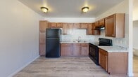 Located at 8028 S Central Ave in Phoenix, Arizona, this single-floor, one-bedroom, one-bathroom unit offers a practical and efficient layout. Light wood-style flooring runs throughout the space, lending a clean and cohesive look to every room. The kitchen is a standout feature, showcasing warm-toned wood cabinetry that extends to the ceiling for ample storage, granite-style countertops, a stainless steel sink, and black appliances including a full-size refrigerator and electric range. A textured ceiling with flush-mount light fixtures provides consistent, even lighting throughout. The bedroom is a comfortable, well-proportioned room with a window that allows natural light to filter in. It includes access to a utility closet housing the water heater, along with built-in shelving for additional storage. The bathroom is straightforward and functional, featuring a full-size soaking tub with an overhead shower, white surround walls, and chrome fixtures. The open-plan living and dining area flows naturally from the kitchen, making the most of the compact footprint. Overall, the unit presents a clean, move-in-ready environment suited for practical, everyday living in the South Phoenix area.