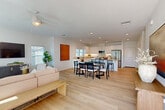 Located at 55150 Monroe St in La Quinta, California, this well-appointed single-story home offers four bedrooms, six bathrooms, and a thoughtfully designed open-concept floor plan. Light wood-style flooring flows throughout the main living areas, complementing the bright, white walls and recessed lighting that give the home a clean, contemporary feel. The living room is bathed in natural light from large sliding glass doors and windows, and features a ceiling fan overhead — a practical touch well-suited to the desert climate. It connects seamlessly to the dining area and kitchen, creating an ideal space for entertaining. The kitchen is outfitted with white shaker cabinetry, light quartz countertops, stainless steel appliances, and a central island with bar seating. A dedicated pantry provides additional storage. The primary bedroom is generously sized, with its own en-suite bathroom featuring dual vanities, white cabinetry with warm countertops, and ample mirror and storage space. Each additional bedroom is bright and comfortable, with natural light from well-placed windows. A dedicated office, six closets, and a full laundry room with side-by-side washer and dryer add to the home's functionality. The attached garage offers substantial storage capacity. Outside, desert-friendly landscaping lines a concrete walkway, with a gated side yard completing the property.