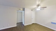 This efficient and thoughtfully designed one-bedroom, one-bathroom unit offers a practical single-floor layout comprising a living room, bedroom, kitchen, bathroom, hallway, and closet. Dark hardwood-style flooring flows consistently throughout, providing a warm, cohesive aesthetic across all rooms.

The living room is a bright, open space anchored by a large sliding glass door dressed with vertical blinds, allowing generous natural light to fill the room. Clean white walls and neutral tones create an airy, minimalist atmosphere.

The galley-style kitchen features dark cabinetry paired with light countertops, a stainless steel sink, and a standout mosaic tile backsplash in grey and white tones. Black appliances, including a full-size refrigerator, complete the functional kitchen setup.

The bedroom is a comfortable, well-proportioned room equipped with a ceiling fan with integrated lighting, a dedicated closet, and a window that brings in natural light. HVAC vents are conveniently positioned for climate control throughout.

The bathroom includes a full-size soaking tub with a shower combo, finished in clean white tile with chrome fixtures, offering a simple and practical bathing space.

Overall, the unit maintains a clean, move-in-ready condition with a neutral palette and consistent flooring that ties each room together seamlessly.