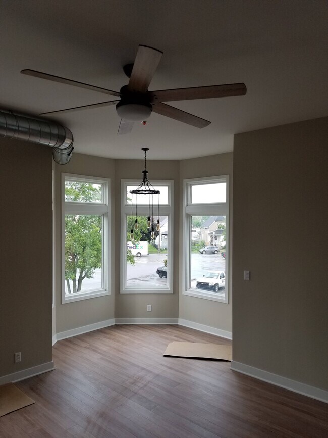 Área de comedor saliente rodeada de ventanas con una lámpara de techo de estilo industrial. - 1548 119th St