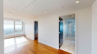 Located on a high floor at 655 Centre St S in Calgary, this sleek and contemporary unit offers an impressive elevated perspective of the city skyline. The layout encompasses two living areas and two full bathrooms, all finished to a high standard with a clean, modern aesthetic throughout.

The living spaces are anchored by rich, warm-toned hardwood flooring that flows seamlessly between rooms, complemented by crisp white walls and recessed lighting. Floor-to-ceiling windows flood the interior with abundant natural light and frame breathtaking panoramic views of Calgary's downtown core and surrounding cityscape, creating a bright and airy ambiance. A built-in kitchen area with white cabinetry and a sleek countertop integrates neatly into the open-plan living space.

The two bathrooms are finished to an exceptional standard, featuring large-format marble-effect tiles on both the floors and walls. The primary bathroom includes a glass-enclosed shower with a deep soaking tub, a floating vanity with a vessel sink, and an expansive wall-mounted mirror, all lending a spa-like quality. The second bathroom maintains the same refined marble aesthetic. Modern frosted and matte-dark panel doors add a distinctive, contemporary touch throughout the unit, tying together the overall sophisticated design.