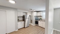 Located at 266 Main St in Windsor Locks, Connecticut, this single-floor, one-bedroom, one-bathroom unit offers a thoughtfully designed layout that maximizes its compact footprint. The open kitchen and living area serve as the heart of the space, featuring crisp white cabinetry, granite-look countertops, and stainless steel appliances including a full-size refrigerator and gas range. A window above the sink brings in natural light, while light-toned luxury vinyl plank flooring flows seamlessly throughout the entire unit, adding warmth and cohesion. The living area provides an open, flexible space with neutral gray walls, white trim, and a front entry door. The bedroom is a comfortable, well-proportioned room with two windows fitted with blinds, allowing ample natural light and privacy. The soft gray walls and matching LVP flooring create a calm, restful atmosphere. The bathroom is clean and functional, featuring a full tub-shower combo with white tile surround, a single vanity with a white cabinet and dark fixtures, and a mirrored medicine cabinet. Textured ceilings are present throughout the unit. Overall, the space presents a fresh, updated aesthetic with consistent finishes across all rooms.
