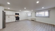 This thoughtfully renovated single-floor unit presents a clean, modern aesthetic defined by a consistent palette of crisp white walls, light-toned luxury vinyl plank flooring, and contemporary gold and brushed nickel fixtures throughout. The open-concept living and kitchen area forms the heart of the space, offering generous room to move and entertain. The kitchen is well-appointed with white shaker cabinetry, a herringbone tile backsplash, light countertops, and a full suite of stainless steel appliances including a gas range, over-the-range microwave, and refrigerator. Recessed lighting and a stylish chandelier illuminate the combined living and dining area, which is further brightened by windows dressed with vertical blinds. A dedicated bedroom provides a quiet retreat, complete with a double-door closet, sputnik-style ceiling fixture, and a window with a vertical blind treatment. The bathroom features slate-style floor tile, white subway wall tile, a floating vanity with a brass faucet, and a mirrored medicine cabinet, offering a polished and functional finish. Baseboard heating units are present throughout, ensuring year-round comfort in this move-in-ready space.