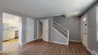 Located at 1245 Granby in Chicopee, Massachusetts, this multi-floor home spans three levels and offers a well-organized layout with a range of functional living spaces. The main level features durable wood-look vinyl plank flooring throughout, neutral gray walls, and a staircase with white railings connecting the floors. The updated kitchen is a standout feature, equipped with white shaker-style cabinetry, granite-look countertops, a stainless steel refrigerator, dishwasher, and electric range, complemented by a pendant light above the sink and a window for natural light. A half bathroom on this level includes a white vanity with a mirrored medicine cabinet. The upper level hosts carpeted bedrooms with generous closet space, baseboard heating, and windows that allow natural light to filter in. A full bathroom on this floor features a tub-shower combination with white tile surround, wood-look flooring, and a window for ventilation. The lower level presents an unfinished basement with exposed wood beam ceilings, concrete block walls, and small egress windows, offering substantial storage capacity or the potential for future finishing. Throughout the home, a consistent gray-and-white color palette creates a clean, cohesive aesthetic.