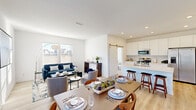This two-story home is designed with a clean, modern aesthetic, characterized by crisp white walls, light wood-tone flooring on the main level, and an abundance of natural light throughout. The main level showcases an open-concept layout where the living, dining, and kitchen areas flow seamlessly together. The living room features large windows with horizontal blinds, allowing generous natural light while offering outdoor views. A comfortable seating area anchors the space, complemented by the adjacent dining area, which accommodates a full-sized table for entertaining.

The kitchen is thoughtfully appointed with white cabinetry, a light quartz countertop island with bar seating, stainless steel appliances, and a distinctive sliding barn door that adds a stylish architectural detail. A half bathroom and staircase with a white-painted banister and warm wood handrail complete the main level.

Upstairs, the bedrooms feature plush carpeting and generous closet space, including walk-in options. One room serves as a dedicated home office, highlighted by floor-to-ceiling vertical blinds and a sliding glass door. The upper level maintains the home's bright, neutral palette, creating a calm and cohesive atmosphere throughout.