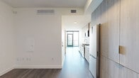 Located at 1331 Columbia Street in San Diego, CA, this modern single-floor unit offers a thoughtfully designed layout comprising a kitchen, living room, bathroom, and balcony. The interior is defined by a clean, minimalist aesthetic, with wide-plank hardwood flooring running throughout and crisp white walls that enhance the sense of openness.

The kitchen is outfitted with floor-to-ceiling cabinetry in a warm wood-grain finish, stainless steel appliances including a gas range and bottom-freezer refrigerator, and a white subway tile backsplash that adds a refined touch. The open living area flows naturally from the kitchen, anchored by a striking exposed concrete accent column that introduces an industrial contrast to the otherwise contemporary palette.

Floor-to-ceiling black-framed sliding glass doors fill the living space with abundant natural light and open directly onto a private balcony, where sweeping views of the San Diego skyline, bay, and surrounding urban landscape create a stunning backdrop. The bathroom features large-format tile flooring and a glass-enclosed shower with dark stone tile surround, delivering a spa-like finish. The unit's efficient layout maximizes every square foot while maintaining a comfortable, airy atmosphere throughout.