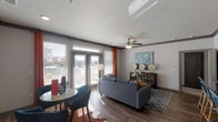 Located in the Willowbend community of Humble, TX, this single-story residence offers a thoughtfully designed open-concept layout with modern finishes and a cohesive contemporary aesthetic throughout. The living area is bright and welcoming, featuring wood-style plank flooring, crown molding, a ceiling fan, and large windows dressed with bold orange curtains that flood the space with natural light. A glass-panel door provides access to an outdoor area, further enhancing the airy feel. The kitchen is a functional centerpiece, equipped with dark cabinetry, stainless steel appliances, granite countertops, and a peninsula breakfast bar illuminated by elegant pendant lighting — ideal for both casual dining and entertaining. The bedrooms offer plush carpeting, ceiling fans, and ample natural light. The primary bedroom connects to a spacious walk-in closet with built-in shelving. Bathrooms are finished with granite-topped dark vanities, a large framed mirror, and a tiled tub-shower combination. The dual-sink primary bath adds a practical luxury touch. Throughout the residence, consistent gray tones, quality materials, and thoughtful details create a polished, comfortable living environment suited for everyday life in Humble, Texas.