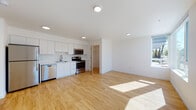 Located at 2348 NW Birdsdale Ave in Gresham, Oregon, this single-floor unit presents a clean, contemporary design with a bright, open-concept layout. Light wood-tone flooring flows throughout the main living areas, complementing the crisp white walls and recessed lighting to create an airy, welcoming atmosphere.

The kitchen is well-appointed with white flat-panel cabinetry, white countertops, and a full suite of stainless steel appliances, including an electric range, over-the-range microwave, dishwasher, and a single-basin sink. An adjacent closet provides additional storage directly off the kitchen.

The open living area benefits from large corner windows that invite generous natural light and offer views of the surrounding neighborhood. The separate bedroom features plush carpeting, a ceiling fan, and a sizable window that further enhances the brightness of the room.

A full bathroom includes a tub/shower combination, a white vanity with integrated sink, and light wood-tone flooring consistent with the rest of the unit. A dedicated laundry area with a stacked washer and dryer unit adds practical convenience. Overall, the space presents a modern, functional, and light-filled environment.