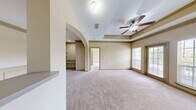 Located at 100 Wesley Stonecrest Circle in Stonecrest, GA, this two-bedroom, two-bathroom residence offers a thoughtfully designed single-floor layout. The galley-style kitchen is outfitted with rich cherry wood cabinetry, a tile backsplash, light countertops, and black appliances including an electric range, built-in dishwasher, and stainless steel refrigerator, all set on stone-look tile flooring. An elegant arched passageway connects the kitchen to the living area, which features a distinctive tray ceiling, crown molding, a ceiling fan, and an exterior door flanked by large windows that flood the space with natural light. Both bedrooms are carpeted and generously sized, each showcasing large windows with outdoor views of the surrounding community. The primary bedroom benefits from additional space and closet access. A hallway with an arched architectural detail adds character to the interior layout. Both bathrooms include tub-shower combinations with white tile surrounds accented by diamond-patterned decorative tiles and brushed nickel fixtures, set on neutral tile flooring. Throughout the residence, warm neutral tones and consistent finishes create a cohesive and inviting ambiance.