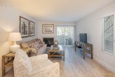 Located in Laguna Niguel, California, this well-appointed single-floor residence offers a thoughtfully designed layout with two bedrooms and two bathrooms. The living room serves as a welcoming centerpiece, featuring a fireplace, light wood-style flooring, and a sliding glass door that brings in natural light and outdoor views. Framed artwork adorns the walls, adding a refined touch to the space.

The kitchen is outfitted with sleek white cabinetry, stainless steel appliances including a gas range, microwave, and refrigerator, complemented by a tray ceiling detail that adds architectural interest. Adjacent to the kitchen, the dining area features light wood flooring, a drum pendant light, and a large wall mirror that enhances the sense of space.

The primary bedroom is carpeted and generously sized, with windows overlooking the greenery outside, providing a serene retreat. The second bedroom offers versatile use, also featuring carpet flooring and a large window with outdoor views. Each bedroom is served by its own bathroom — one featuring a lighted vanity mirror and updated wood-look flooring, and the other finished in neutral tones with a tub-shower combination. The overall ambiance is clean, bright, and move-in ready.