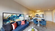 This well-appointed single-floor residence showcases a thoughtfully designed open-concept layout that seamlessly connects the kitchen, dining, and living areas. The kitchen is a functional centerpiece, featuring white cabinetry, a granite countertop island with bar seating, stainless steel appliances including a refrigerator, range, and microwave, and elegant pendant lighting overhead. Wood-look flooring runs throughout the main living areas, lending warmth and continuity to the space.

The living area is bright and welcoming, with large windows that invite abundant natural light and offer views of the surrounding urban streetscape. The dining space sits comfortably between the kitchen and living room, creating a natural flow ideal for both everyday living and entertaining.

The bedroom is generously sized with plush carpeting and features sliding glass doors that open directly onto a private balcony, providing outdoor access and additional natural light. A mirrored closet adds both function and a sense of depth to the room.

The bathroom is clean and well-finished, with granite-topped vanity cabinetry, a large mirror, and light tile flooring. A louvered closet door in the hallway adds a classic architectural touch. Overall, the residence offers a contemporary aesthetic with practical, high-quality finishes throughout.