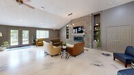 Located at 3099 Kirklevington Drive in Lexington, Kentucky, this single-floor community space offers a thoughtfully designed layout across a comfortable footprint. A striking marbled epoxy floor runs seamlessly throughout, lending a cohesive and contemporary aesthetic to every area.

The central lounge area serves as the heart of the space, anchored by a dramatic stacked-stone accent wall housing a sleek linear fireplace and mounted television. Built-in shelving flanks the feature wall on both sides, providing display space and adding architectural depth. Vaulted ceilings, recessed lighting, and a modern globe pendant fixture contribute to an open, inviting atmosphere, while multiple windows allow natural light to fill the room.

The kitchen is well-equipped with rich dark-wood cabinetry, granite countertops, stainless steel appliances including a French door refrigerator, and a breakfast bar with seating. A window above the counter provides natural light and outdoor views of the surrounding greenery.

The dining area accommodates multiple high-top tables and chairs beneath stylish globe pendant lights and a ceiling fan, making it well-suited for group gatherings. Patterned wallcovering adds visual interest to this zone.

A restroom with a floating vanity and mirrored wall completes the space. Additional doors suggest private rooms or storage areas throughout.