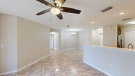 Located at 200 Dahlia Lane in Fort Myers, Florida, this well-appointed single-story home offers three bedrooms, two bathrooms, and a thoughtfully designed layout. Light-toned ceramic tile flooring flows consistently throughout the interior, reflecting natural light and contributing to a clean, cohesive aesthetic.

The open living and dining area is anchored by ceiling fans and connected via an elegant arched passageway, adding architectural character to the space. A chandelier accents the dining area, while large windows invite ample natural light. The kitchen is equipped with stainless steel appliances including a refrigerator, range, microwave, and dishwasher, complemented by warm taupe cabinetry, light countertops, a double sink, and recessed lighting. A pantry with bi-fold doors provides generous storage.

The bedrooms are bright and well-sized, each featuring ceiling fans and distinctive arched windows with shutters that frame views of the surrounding greenery. Each bedroom includes closet storage. The primary bedroom is notably spacious and is served by an en-suite bathroom featuring a dual-sink vanity with dark cabinetry, a soaking tub, a separate walk-in shower, and a window for natural light. The second bathroom offers a full tub-shower combination with white tile surround.

Outside, the property is framed by manicured hedgerows and mature pine trees, offering a serene, park-like setting.