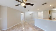 Located at 200 Dahlia Lane in Fort Myers, Florida, this well-appointed single-story home offers three bedrooms, two bathrooms, and a thoughtfully designed layout. Light-toned ceramic tile flooring flows consistently throughout the interior, reflecting natural light and contributing to a clean, cohesive aesthetic.

The open living and dining area is anchored by ceiling fans and connected via an elegant arched passageway, adding architectural character to the space. A chandelier accents the dining area, while large windows invite ample natural light. The kitchen is equipped with stainless steel appliances including a refrigerator, range, microwave, and dishwasher, complemented by warm taupe cabinetry, light countertops, a double sink, and recessed lighting. A pantry with bi-fold doors provides generous storage.

The bedrooms are bright and well-sized, each featuring ceiling fans and distinctive arched windows with shutters that frame views of the surrounding greenery. Each bedroom includes closet storage. The primary bedroom is notably spacious and is served by an en-suite bathroom featuring a dual-sink vanity with dark cabinetry, a soaking tub, a separate walk-in shower, and a window for natural light. The second bathroom offers a full tub-shower combination with white tile surround.

Outside, the property is framed by manicured hedgerows and mature pine trees, offering a serene, park-like setting.