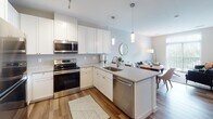 Located at 2805 Clinton Ave in Cleveland's vibrant 44113 zip code, this single-floor residence offers a thoughtfully designed layout with modern finishes throughout. The open-concept kitchen is a standout feature, showcasing crisp white shaker cabinetry extending to the ceiling, stainless steel appliances including a refrigerator, electric range, microwave, and dishwasher, complemented by quartz-style countertops and a subway tile backsplash. A peninsula with pendant lighting connects seamlessly to the dining and living areas, where large windows with vertical blinds invite abundant natural light and outdoor views. The living space provides a warm, inviting ambiance with wood-style flooring flowing throughout the main areas. The bedrooms are carpeted and serene, with one featuring a sliding glass door to an outdoor view and ample wall space. A spacious walk-in closet with wire shelving connects directly to a full bathroom, offering practical convenience. The bathrooms are finished with white cabinetry, quartz countertops, brushed gold fixtures, large mirrors, and a glass-enclosed walk-in shower, all accented by wood-style flooring. The overall aesthetic is clean, contemporary, and cohesive, making this residence a comfortable and stylish home in Cleveland.
