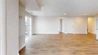 This well-appointed 2-bedroom, 2-bathroom residence is thoughtfully laid out on a single floor, offering a comfortable and functional living environment. The open-concept kitchen and living area forms the heart of the home, with light wood-grain flooring running throughout and large windows that invite abundant natural light and outdoor views. The kitchen is equipped with stainless steel appliances — including a refrigerator, range, microwave, and dishwasher — complemented by white cabinetry, dark countertops, and a classic white tile backsplash. The spacious living area provides generous room for furnishing and flows seamlessly from the kitchen. The primary bedroom is notably roomy, featuring a large window with exterior views and access to a dedicated walk-in closet with built-in shelving and hanging rods. The second bedroom is well-sized with its own closet access and connects easily to the hallways. Both bathrooms are clean and functional, with one featuring a full soaker tub and shower surround equipped with grab bars. Two hallways guide the layout efficiently, and a welcoming entrance completes the floor plan. Neutral warm-beige walls and recessed lighting throughout lend the space a bright, contemporary ambiance.