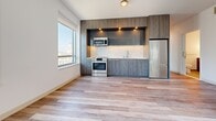 Located at 1177 Market St in the heart of San Francisco, this modern unit offers a clean, contemporary design throughout its single floor layout. Light-toned wood plank flooring runs consistently across all living areas, creating a cohesive and airy aesthetic complemented by crisp white walls and clean baseboards.

The open kitchen is a standout feature, outfitted with wood-toned cabinetry in both upper and lower configurations, stainless steel appliances including a range, built-in microwave, and full-size refrigerator, and a sleek countertop with an integrated sink. A large window in the kitchen frames a striking view of the San Francisco City Hall dome, filling the space with natural light.

The living and sleeping areas are generously proportioned, each benefiting from large windows that invite abundant natural light and offer dynamic views of the surrounding urban skyline. Wall-mounted heating units provide climate control throughout. A louvered-door closet adds practical storage to one of the bedrooms.

The bathroom is finished to a high standard, featuring large-format floor tiles, a double-sink vanity with dark wood cabinetry, a wide mirror with integrated lighting, and a glass-enclosed shower with marble-style wall panels. The overall ambiance of the space is clean, bright, and well-suited to modern urban living in one of San Francisco's most central neighborhoods.