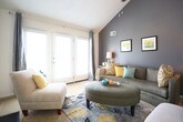 This two-story residence in Virginia Beach offers a well-designed layout across two floors. The living room is a standout space, featuring a dramatic vaulted ceiling with a bold slate-gray accent wall, large windows that invite natural light, and carpeted flooring that adds warmth throughout. A staircase with a classic baluster railing connects the two levels, visible from the open interior view.

The kitchen is outfitted with rich dark wood cabinetry, granite-style countertops, a stainless steel sink, and a full suite of appliances including an electric range with overhead ventilation, all set on tile flooring.

The dining area is bright and inviting, highlighted by a vaulted ceiling detail, generous windows with decorative curtains, and a pendant light fixture overhead.

The primary bedroom features plush carpeting, dual windows for ample natural light, and comfortable proportions. Additional bedrooms are equally well-appointed with carpet flooring and natural light.

Bathrooms include tile flooring, wood-toned vanity cabinetry, and one features a shower-tub combination. A dedicated laundry room with washer and dryer hookups, water heater, and electrical panel provides practical utility space, accessible conveniently from one of the bathrooms.