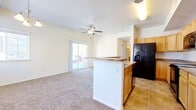 Located at 3626 W 29th St in Greeley, Colorado, this single-story residence offers a functional, open-concept layout that connects the kitchen and living areas seamlessly. The kitchen is equipped with light wood cabinetry, granite-style countertops, black appliances including a refrigerator with ice dispenser, electric range, and built-in microwave. A peninsula with a breakfast bar serves as a natural divider between the kitchen's tile flooring and the carpeted living area, providing both additional counter space and a casual dining option. The living room is bright and open, featuring a ceiling fan and a sliding glass door that allows natural light and provides access to the outdoors. The bedroom features plush carpet, a ceiling fan, a tray ceiling detail, and a window that brings in natural light. The bathroom is finished with tile flooring and includes a full tub and shower combination with built-in shelving. A dedicated in-unit laundry area accommodates a full-size, top-loading washer and dryer. Overall, the space presents a clean, practical layout suited for comfortable everyday living.