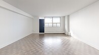 This well-appointed 2-bedroom, 1-bathroom unit at 2450 Weston Road in Toronto offers a clean, modern aesthetic across a comfortable single floor. The entryway features a tiled hallway with a dedicated closet, providing a practical transition into the main living areas. The open kitchen is a standout feature, outfitted with crisp white cabinetry, a classic subway tile backsplash, dark countertops, and a full suite of stainless steel appliances including a refrigerator, stove, microwave, and dishwasher. Light tile flooring and a peninsula counter add both functionality and style. The spacious living room is bathed in natural light and showcases classic parquet wood flooring, white walls, and a bold navy accent door that opens to an outdoor-facing window. Both bedrooms continue the parquet flooring theme and feature large windows that invite abundant natural light and views of the surrounding neighbourhood. The generously sized primary bedroom offers ample room for furnishings. The bathroom is finished with full-height white subway tile surrounding a soaker tub and shower combination with chrome fixtures, maintaining the unit's clean, cohesive design throughout.