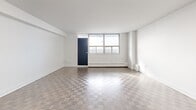 This well-appointed 2-bedroom, 1-bathroom unit at 2450 Weston Road in Toronto offers a clean, modern aesthetic across a comfortable single floor. The entryway features a tiled hallway with a dedicated closet, providing a practical transition into the main living areas. The open kitchen is a standout feature, outfitted with crisp white cabinetry, a classic subway tile backsplash, dark countertops, and a full suite of stainless steel appliances including a refrigerator, stove, microwave, and dishwasher. Light tile flooring and a peninsula counter add both functionality and style. The spacious living room is bathed in natural light and showcases classic parquet wood flooring, white walls, and a bold navy accent door that opens to an outdoor-facing window. Both bedrooms continue the parquet flooring theme and feature large windows that invite abundant natural light and views of the surrounding neighbourhood. The generously sized primary bedroom offers ample room for furnishings. The bathroom is finished with full-height white subway tile surrounding a soaker tub and shower combination with chrome fixtures, maintaining the unit's clean, cohesive design throughout.