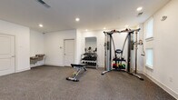 Located at 11310 Vandelay Court in Charlotte, NC, this well-appointed fitness center offers a comprehensive workout environment across a single floor. The space is finished with clean white walls, recessed lighting, and durable rubber-composite flooring designed to withstand heavy use while providing comfort underfoot.

The facility is organized to accommodate a full range of exercise modalities. A dedicated cardio zone features multiple treadmills and is bathed in natural light from large windows that overlook lush greenery, creating an inviting atmosphere for extended training sessions. A separate area houses an elliptical trainer and a stationary bike, providing additional low-impact cardio options alongside private room access.

The strength training section is well-equipped with a Hoist functional trainer cable machine, a full rack of dumbbells ranging across multiple weight increments, a full-length mirror for form monitoring, and an adjustable workout bench. A water fountain station is conveniently positioned nearby for easy hydration access.

Double doors provide a direct exterior entry point, enhancing ventilation and accessibility. The space maintains a bright, open feel throughout, supported by consistent recessed lighting and a neutral color palette. This fitness center delivers a practical and complete workout facility suited to a variety of fitness goals and routines.