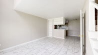 Located at 9430 Concourse Dr in Houston, TX, this multi-level home spans three floors, offering a well-organized layout with distinct living spaces across each level. The ground floor serves as the main living area, featuring striking marble-look tile flooring that flows through the open living room, dining area, and kitchen. The living room is bright and spacious, with a large window that fills the space with natural light and a staircase positioned along one wall. The kitchen is functional and well-equipped, featuring taupe cabinetry, white appliances, a built-in range hood, and ample storage including a dedicated pantry. A convenient pass-through counter connects the kitchen to the living space, complemented by a built-in shelving unit that adds character and utility. The second floor offers carpeted living space with vaulted ceilings, a decorative railing detail, and access to additional rooms including a closet fitted with built-in shelving. Two bathrooms are present within the home, one featuring marble-look tile flooring and a full tub-shower combination. The top floor opens to a private rooftop terrace finished with brick pavers and enclosed by a black metal railing, offering open-air views of the surrounding neighborhood and mature trees. Neutral tones and clean finishes create a cohesive, move-in-ready atmosphere throughout.