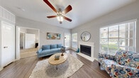 This single-floor residence offers a thoughtfully designed layout that balances comfort and functionality across its key living areas. The living room serves as the heart of the home, showcasing a white-mantled fireplace, rich wood-look flooring, and vaulted ceilings equipped with a ceiling fan. Natural light pours in through multiple windows adorned with white blinds, and a glass door provides direct outdoor access, enhancing the open, airy atmosphere of the space.

The kitchen is outfitted with grey cabinetry, light granite-style countertops, a mosaic tile backsplash, and a full suite of black appliances including a refrigerator, electric range, and microwave. A double basin sink and generous counter space make the kitchen both practical and visually cohesive. Conveniently adjacent to the kitchen is an in-unit laundry closet.

Both bedrooms feature plush carpeting, ceiling fans, and windows that bring in natural light. One bedroom includes a walk-in closet with built-in organization, while the other offers direct access to an additional closet. The bathroom is finished with grey cabinetry, a single vanity with a wide mirror, and wood-look tile flooring, completing the home's consistent, neutral design palette.