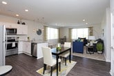 This single-floor residence offers a thoughtfully designed layout that balances comfort and functionality across its key living spaces. The living room is generously sized, featuring plush wall-to-wall carpeting, recessed lighting, and large windows dressed with patterned curtains that allow abundant natural light and outdoor views to fill the room. The open, airy feel is enhanced by neutral wall tones throughout.

The kitchen is well-equipped with crisp white shaker-style cabinetry, granite countertops, and a full suite of stainless steel appliances, including a refrigerator, range, microwave, and dishwasher. Wood-look plank flooring runs through the kitchen, adding warmth and durability to the space.

The bedrooms are carpeted and comfortably proportioned, each featuring ceiling fans with light fixtures and windows that bring in natural light. One bedroom includes access to a spacious walk-in closet outfitted with multiple hanging rods and shelving along two walls, offering ample storage.

The bathroom continues the wood-look flooring seen in the kitchen and features granite-topped vanity cabinetry and a shower-tub combination, completing this practical and cohesive residence.